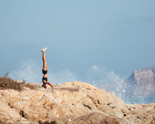 Woman doing headstand on rocks near the Pacific Ocean in Mazatlan Mexico